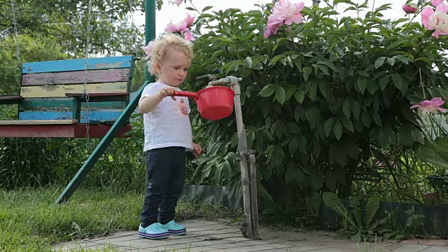 小女孩在玩盛水的勺子。视频素材
