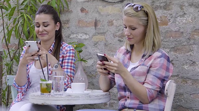 十几岁的女孩在咖啡馆用智能手机视频下载