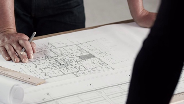 建筑师一边用铅笔画图纸，一边向别人解释细节视频素材