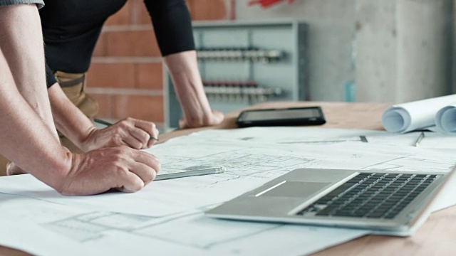 男建筑师和女建筑师在桌子上绘制图纸，做笔记，并使用笔记本电脑进行规格说明视频素材