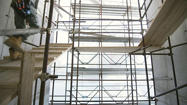 工人们正把白色波纹管抬上建筑工地的脚手架楼梯视频素材