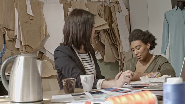 亚洲女裁缝工作的笔记本电脑和聊天的同事视频素材