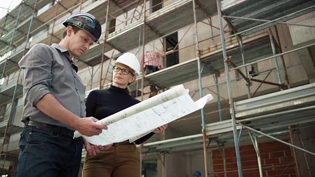 男建筑师和女建筑师在工地外面看平面图视频素材