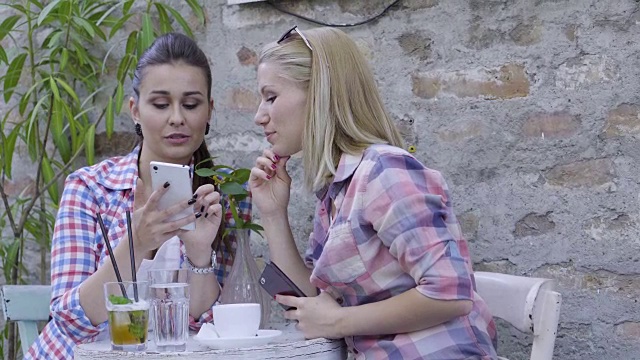 十几岁的女孩在咖啡馆用智能手机视频下载