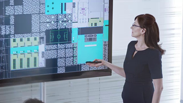 女建筑师正在向坐在会议室里的同事们展示一个大屏幕上的计划视频素材