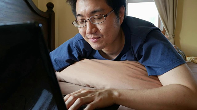 快乐的亚洲人使用笔记本电脑在床上聊天视频素材