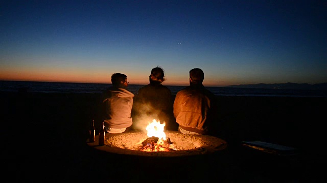 朋友们在海滩篝火边看日落视频素材