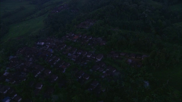 郁郁葱葱起伏的小山环绕着一个小村庄。视频下载