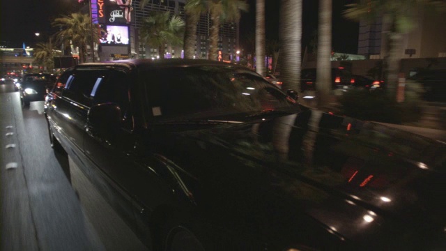 晚上，一辆豪华轿车在拉斯维加斯的街道上行驶时，灯光映照在上面。视频素材