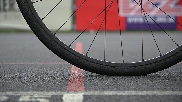 英国赛车场上，一辆自行车的前轮被推向起跑线的近距离、低水平的镜头。视频下载
