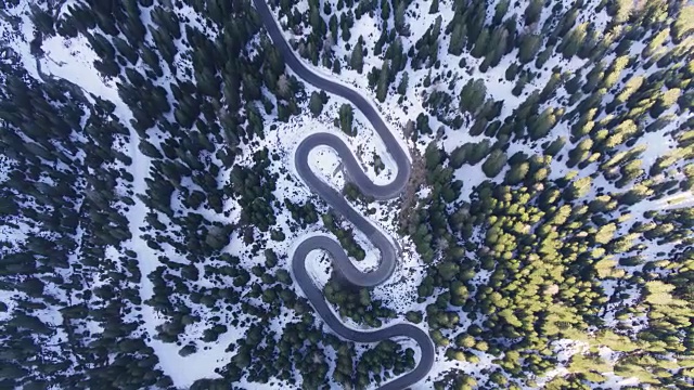 无人机拍摄的冬季森林中蜿蜒的道路视频下载