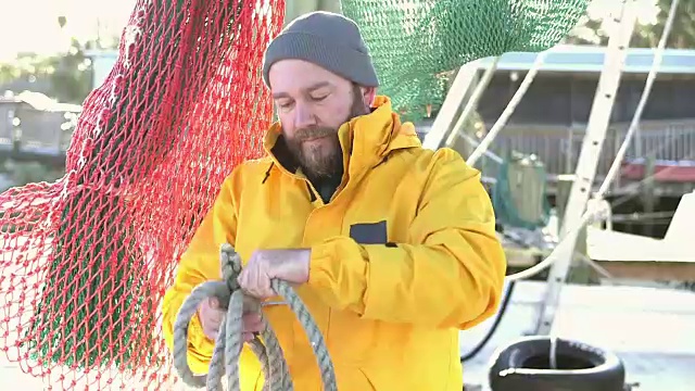 在商业渔船上卷绕绳索的工人视频素材