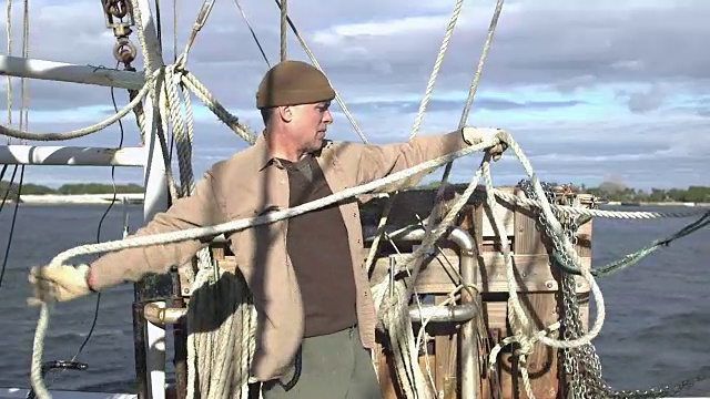 在商业渔船上卷绕绳索的工人视频素材