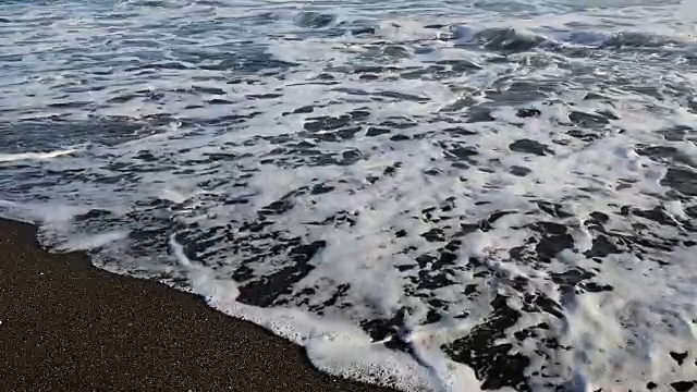 在印尼巴厘岛的黑沙滩上，海浪拍打着沙滩视频下载