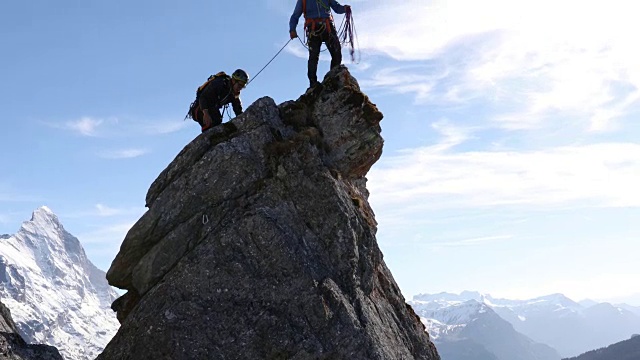 男性登山运动员攀登岩石的顶峰，下面是山脉视频下载