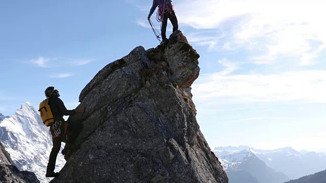男登山运动员攀登岩石顶峰，领队抛绳视频素材