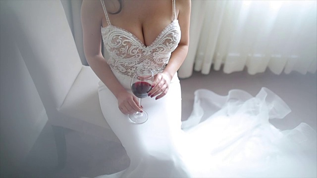 迷人的新娘与一杯酒在她的婚纱摆姿势视频下载
