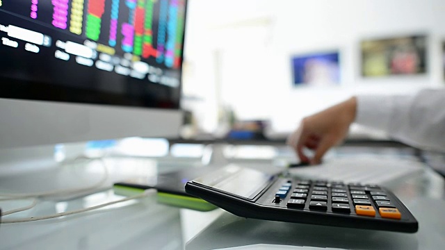 商人在办公室用数字平板电脑和笔记本电脑分析股市视频下载