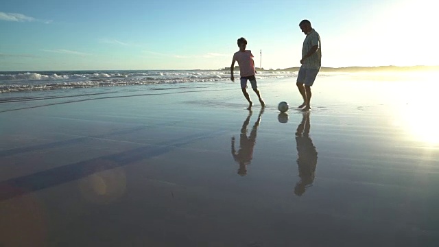 日落时分在海滩上踢足球视频素材