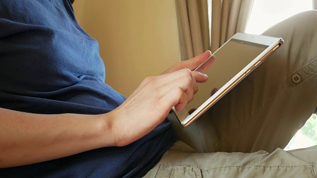 身穿蓝色t恤的男子在床上使用数码平板电脑——室内场景视频下载