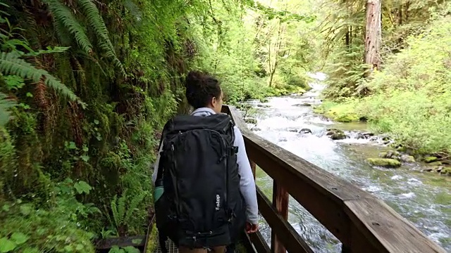 一个沿着小溪背包旅行的年轻女子视频下载