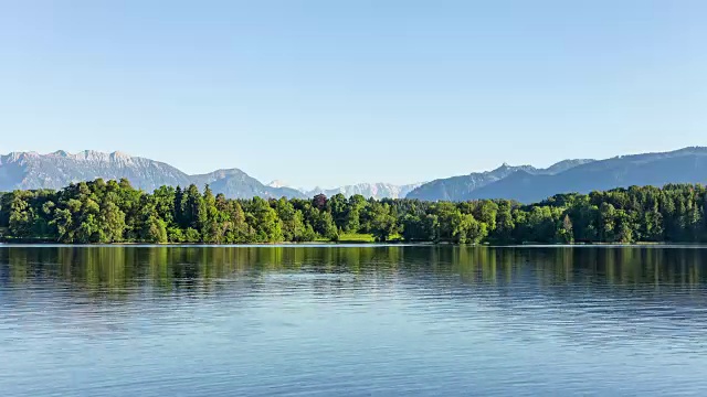 在一个阳光明媚的日子里，从正午到日落，玻璃般清澈的水面和湛蓝的天空在巴伐利亚湖上的小露营岛伯尔瑙拍摄的简单的时间流逝视频素材