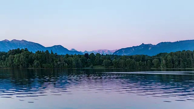 从夜晚到白天的过渡延时——拍摄于巴伐利亚州斯塔夫尔湖上的小露营岛伯诺——月亮在深蓝色的水中的倒影——在日出时结束视频素材