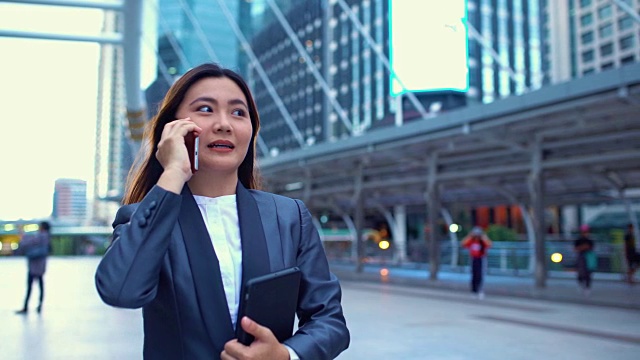 女商人在城市里用手机，跟踪拍摄视频素材