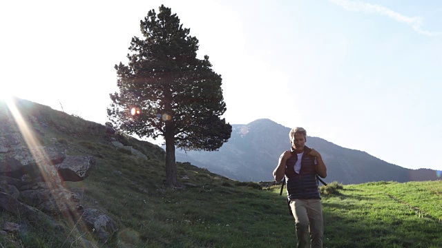 一个徒步旅行者在日出时沿着小路向山上走去视频素材