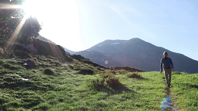 一个徒步旅行者在日出时沿着小路向山上走去视频素材
