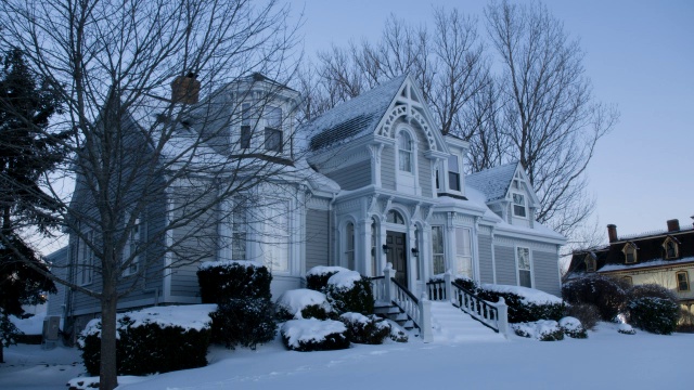 广角多层房屋被雪覆盖。灌木和乔木可见。视频下载