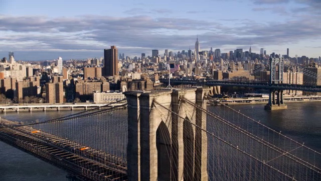 布鲁克林大桥的天线。东河。纽约城的天际线上有摩天大楼和高层的办公室或公寓大楼。美国国旗。bg的曼哈顿大桥。视频下载