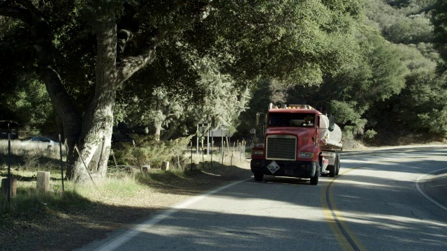 中等角度的油罐车在乡村道路上倒车或倒车行驶。卡车格栅。视频下载