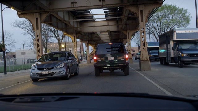 广角驾驶pov直行跟随越野车，接近碰撞。城市街道在高架铁轨下。可能是汽车追逐的一部分。视频素材