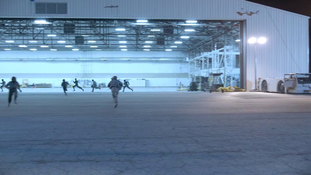 从右到左的士兵在军事基地上奔跑。fg的机库和军用吉普车。可能是攻击或入侵。视频下载
