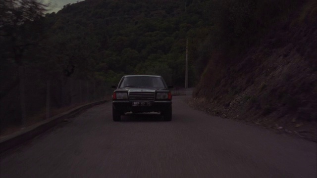 在弯弯曲曲的山路上，一辆摩托车跟在一辆奔驰后面。视频素材