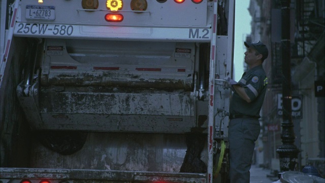 在苏豪区，工人们从垃圾车上跳下来，在街上倒垃圾。视频素材