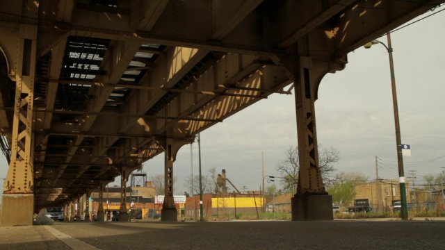 在城市街道高架铁轨下行驶的汽车的中等角度。迂回。可能是汽车追逐的一部分。视频素材