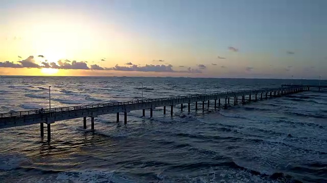 日出码头沿着天堂海滩上的汹涌海浪视频素材