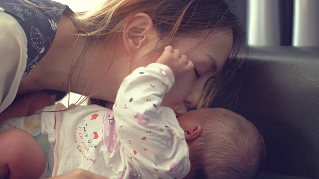 年轻的母亲亲吻她的新生儿视频素材