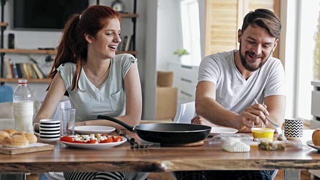 幸福的夫妇在家里吃早餐，在餐桌上交流。视频素材