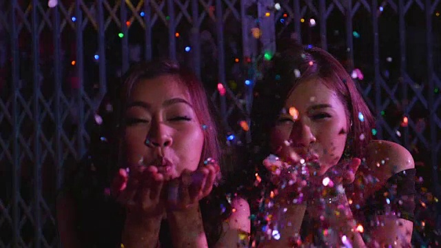 慢镜头里，两个女孩在派对上用手吹五彩纸屑视频下载