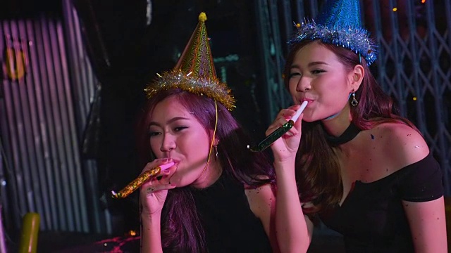 两个女孩玩派对喇叭吹风机在慢动作视频下载