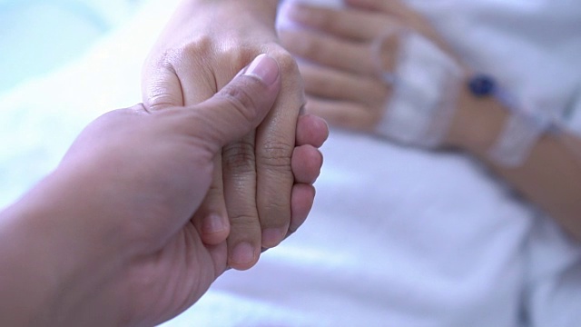亚洲病人在床上握着家人的手视频素材