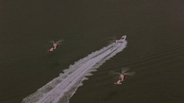 三架直升机在一座桥附近追赶一艘摩托艇。视频素材