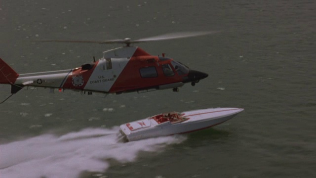 一架直升机飞近一艘高速行驶的汽艇。视频素材