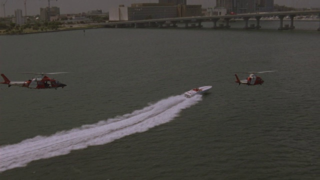 两架直升机在一座桥附近追赶一艘摩托艇。视频素材