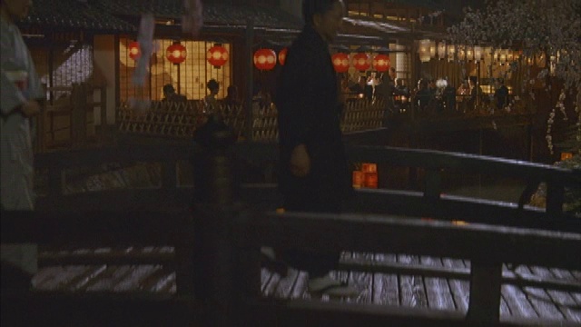 红黄相间的纸灯笼在桥下顺流而下。广场灯笼上写着汉字。吊车上的镜头显示了正在过桥的男男女女。穿西装、戴帽子或和服的男人。女性视频素材