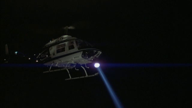 一架带探照灯的警用直升机夜间在城市上空盘旋视频下载