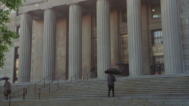 下雨时，人们打着雨伞进出纽约法院大楼。视频素材